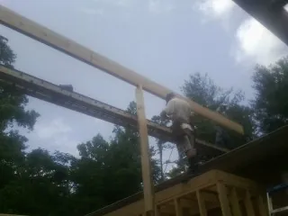 Carpenter setting a ridge beam over a new addition frame — Ice Dam Removal by Roofing Brothers in Lowden