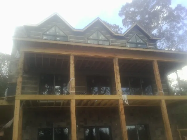 Dormers and porch framing on a large log home under construction — Roof Coating work by our crew in Lowden