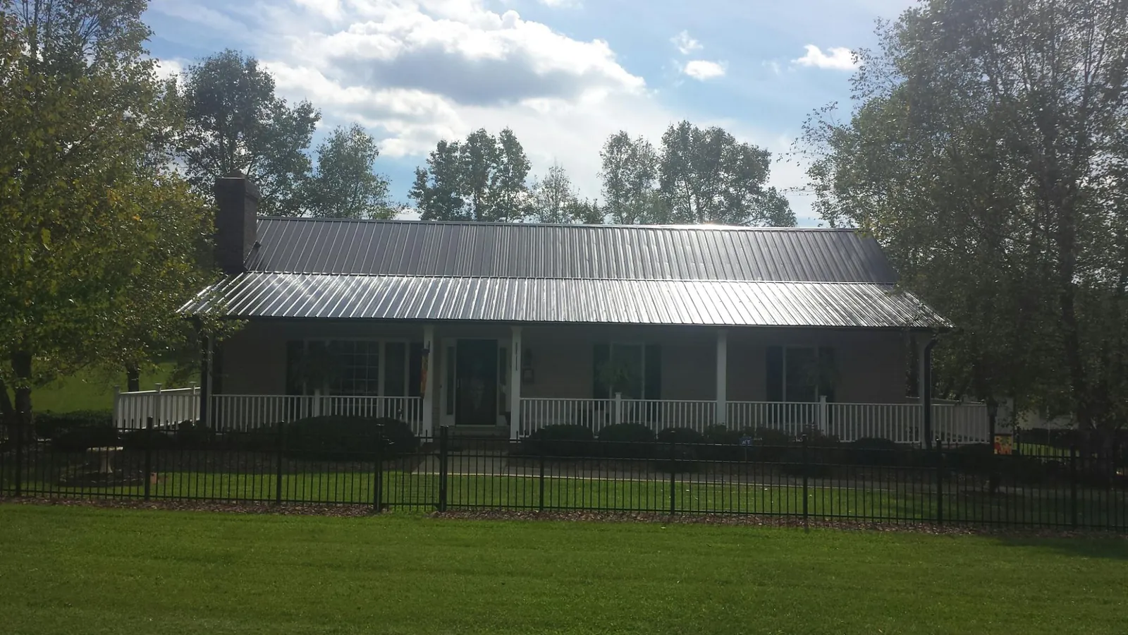 Gray metal roof on a brick ranch with a full width front porch — Gutter Guard Installation work by our crew in Lowden