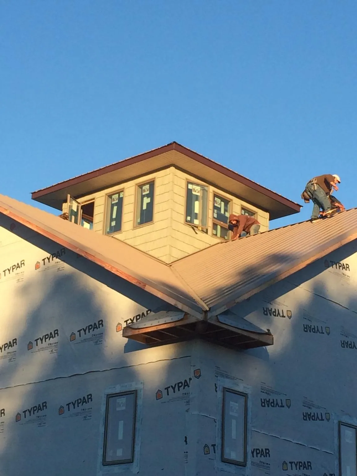 Roofers working around a rooftop cupola on a new metal roof at sunset — Roof Waterproofing in Lowden by Roofing Brothers